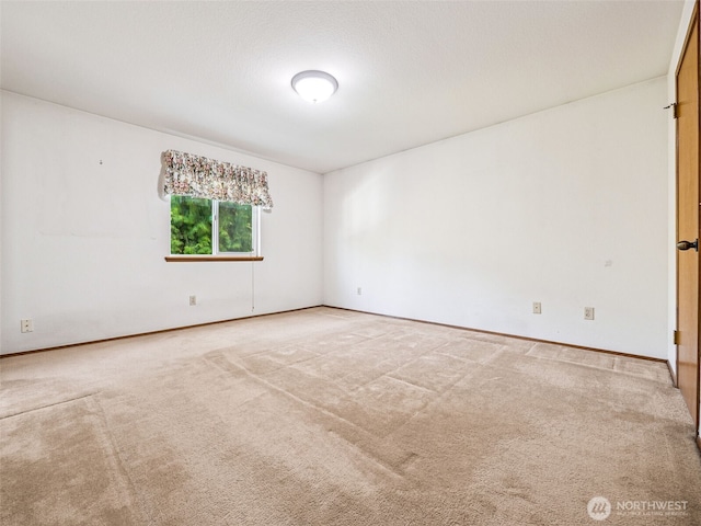 carpeted spare room featuring baseboards