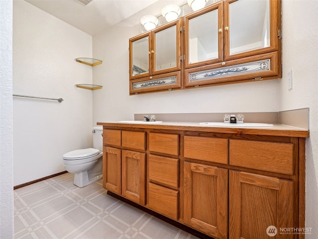 bathroom with double vanity, toilet, tile patterned floors, and a sink
