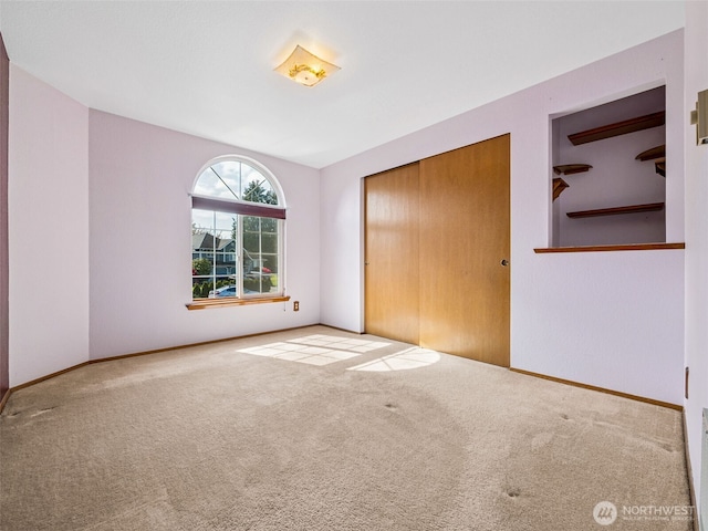 unfurnished bedroom with carpet floors, baseboards, and a closet