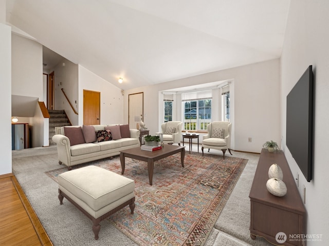 living room with high vaulted ceiling, stairs, and wood finished floors