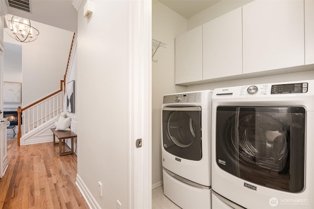 11628 NE 100th St, Kirkland, WA 98033 - laundry room featuring cabinet space, washer and clothes dryer, light wood finished floors, a chandelier, and baseboards