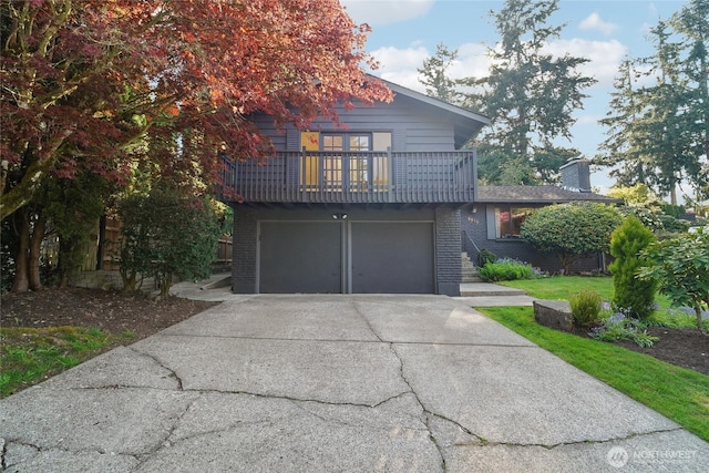 view of front of home featuring driveway, a front yard, brick siding, a balcony, and an attached garage