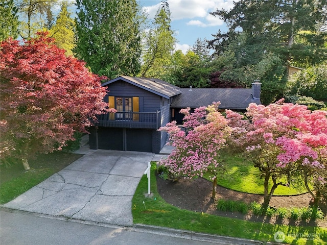 view of front of property featuring a garage, concrete driveway, and a balcony