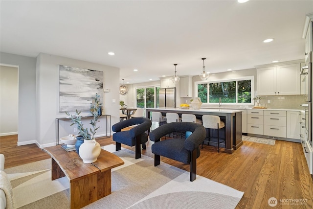 living area with recessed lighting, light wood finished floors, and baseboards