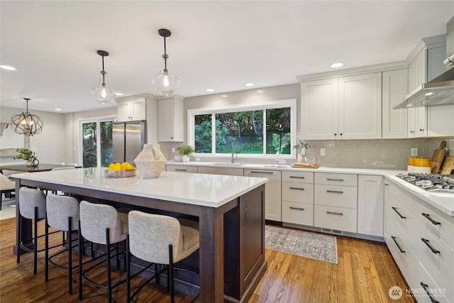 kitchen with backsplash, light countertops, appliances with stainless steel finishes, and wood finished floors