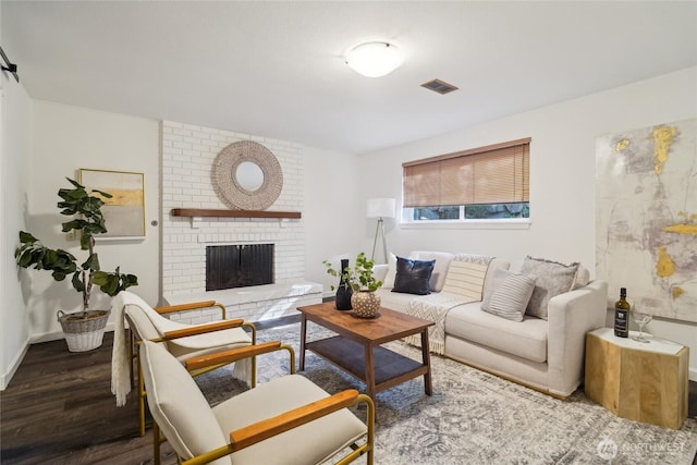 living area with baseboards, wood finished floors, visible vents, and a fireplace