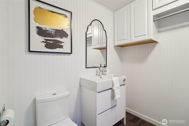 half bath featuring vanity, wood finished floors, and toilet