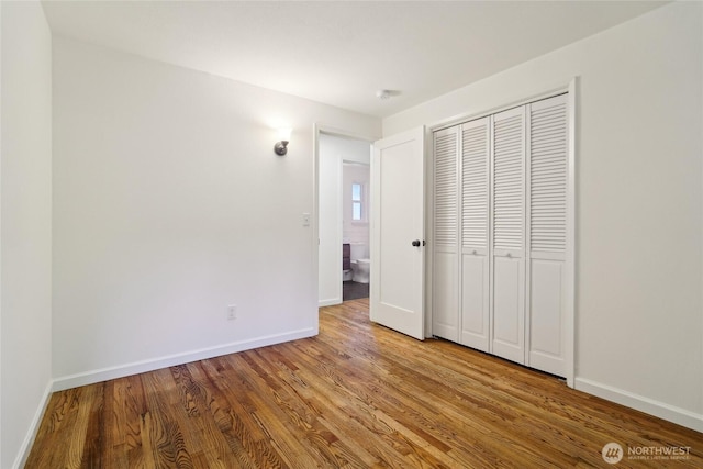 unfurnished bedroom with baseboards, wood finished floors, and a closet