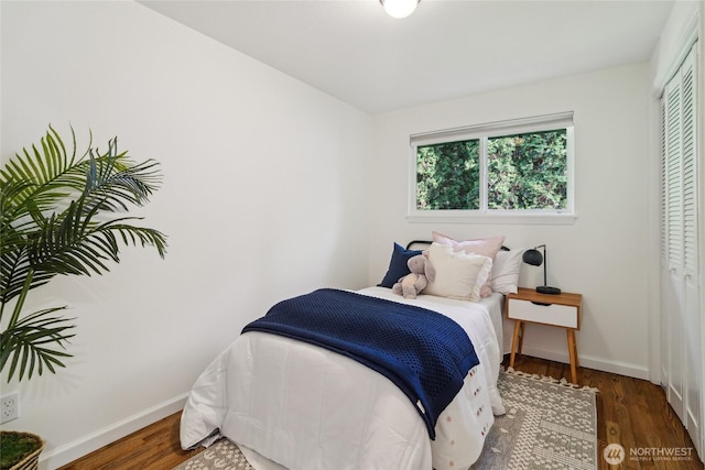 bedroom featuring baseboards, wood finished floors, and a closet