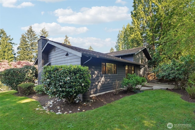 view of side of property with a lawn and a chimney