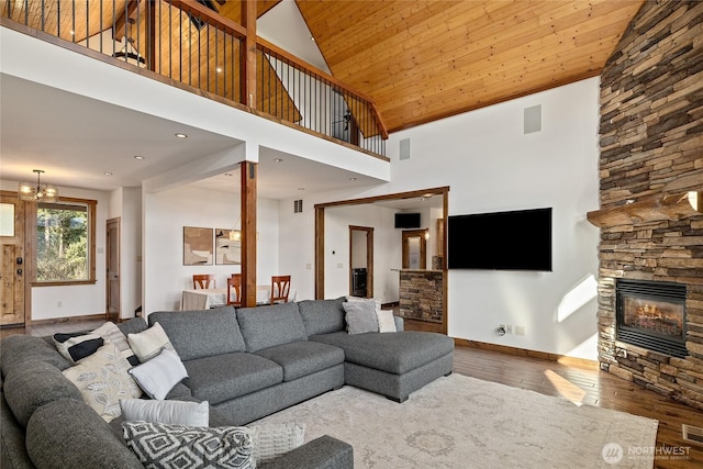 living room featuring wood-type flooring, a fireplace, a notable chandelier, and baseboards