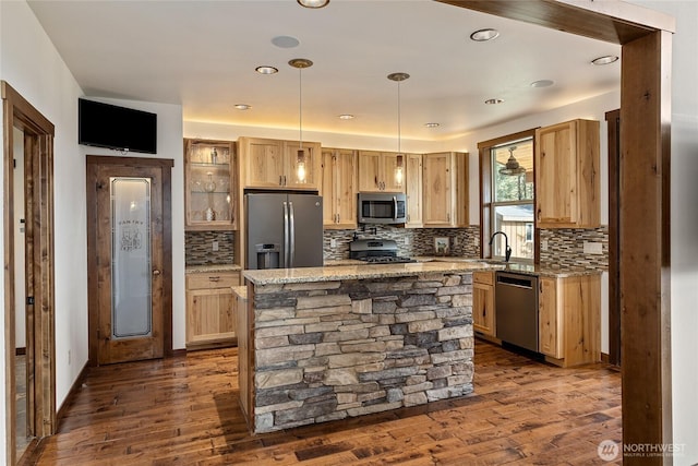 kitchen featuring dark wood finished floors, glass insert cabinets, decorative backsplash, stainless steel appliances, and a kitchen island