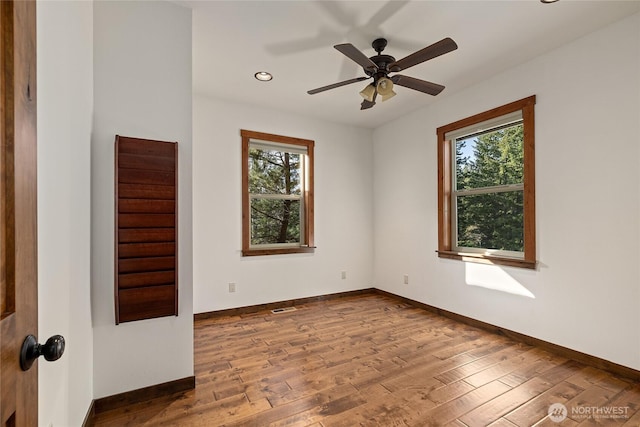 unfurnished room with a wealth of natural light, wood finished floors, and baseboards