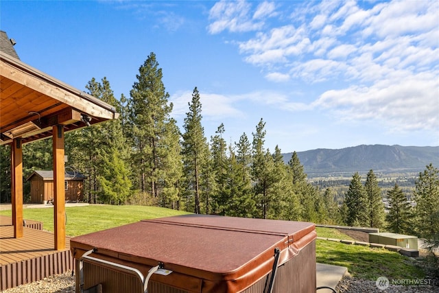 deck with an outbuilding, a hot tub, a storage shed, a mountain view, and a lawn