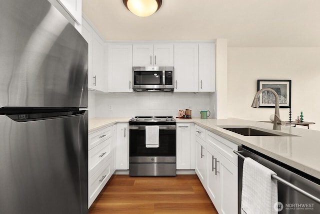 kitchen featuring decorative backsplash, appliances with stainless steel finishes, a sink, light countertops, and white cabinets