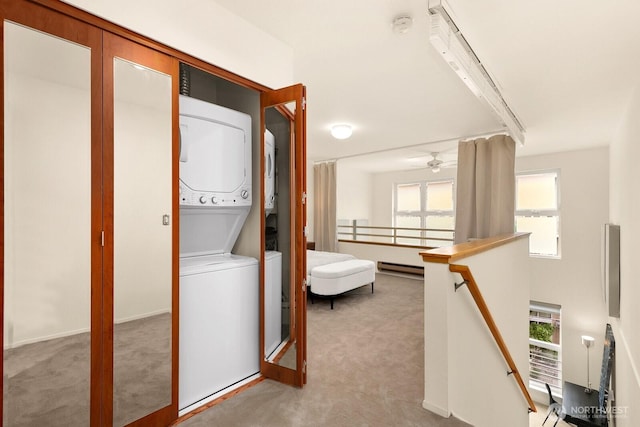 laundry area with light colored carpet, laundry area, a baseboard heating unit, and stacked washer / drying machine