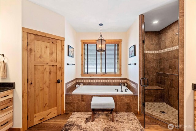 bathroom with a garden tub, wood finished floors, and a shower stall