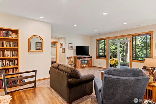 carpeted living area with recessed lighting, baseboards, and a glass covered fireplace