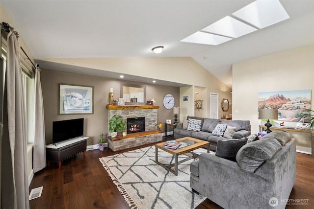 living area featuring a stone fireplace, lofted ceiling with skylight, wood finished floors, and visible vents