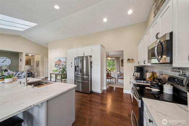 kitchen with a sink, white cabinets, light stone countertops, and stainless steel appliances