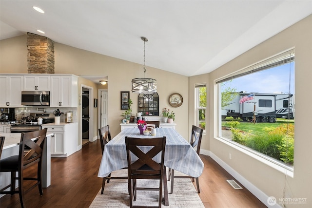 dining area featuring visible vents, stacked washing maching and dryer, plenty of natural light, and lofted ceiling