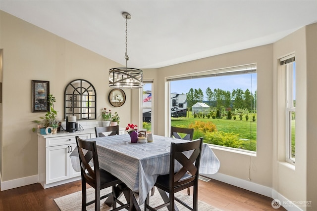 dining space featuring a healthy amount of sunlight, baseboards, wood finished floors, and a notable chandelier