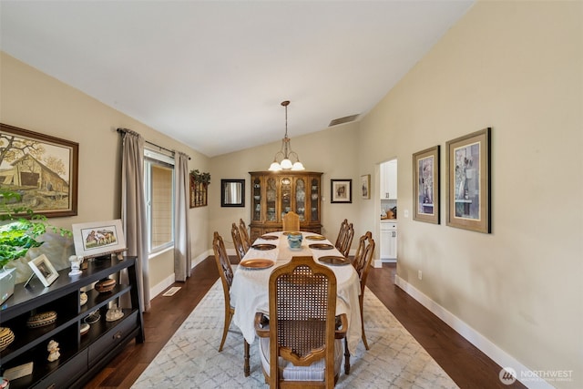 dining room with baseboards, visible vents, vaulted ceiling, and an inviting chandelier