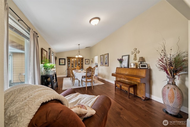 living room featuring baseboards, dark wood-style flooring, a notable chandelier, and vaulted ceiling