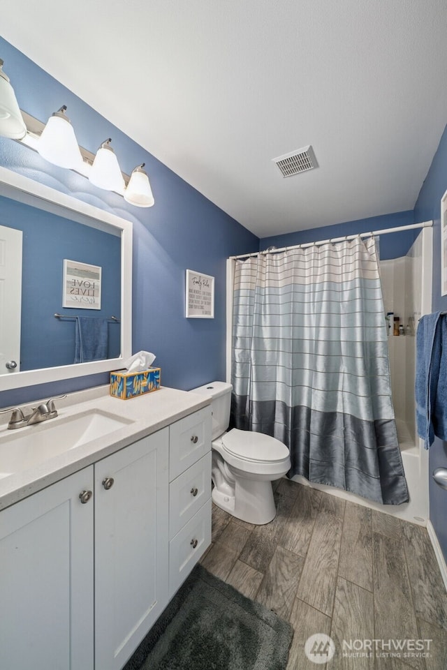 bathroom featuring visible vents, shower / tub combo with curtain, vanity, wood finished floors, and toilet