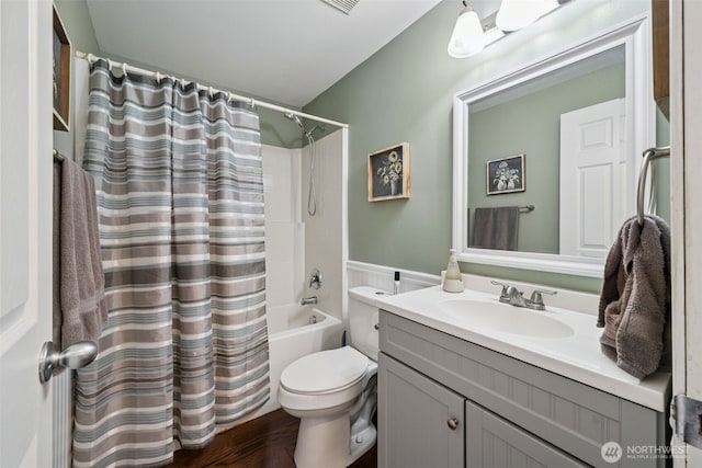 bathroom with vanity, wainscoting, wood finished floors, shower / bath combination with curtain, and toilet