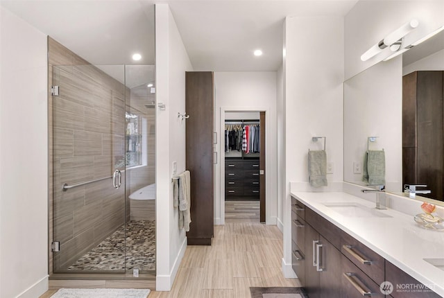 bathroom featuring double vanity, baseboards, a sink, and a stall shower