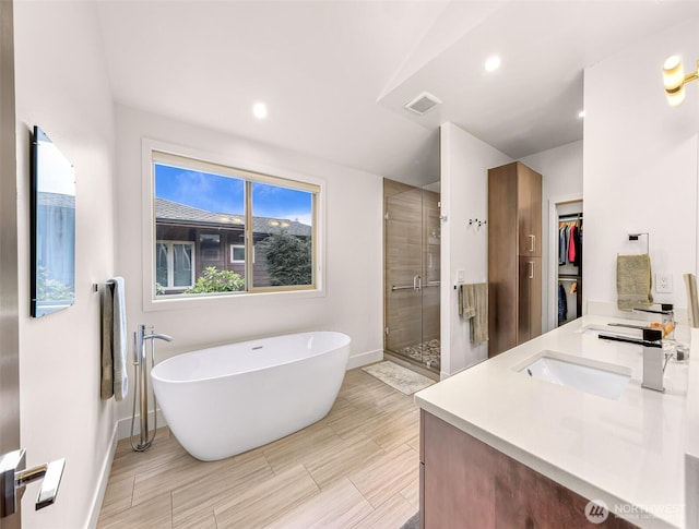 full bathroom with baseboards, a spacious closet, a shower stall, and a freestanding tub