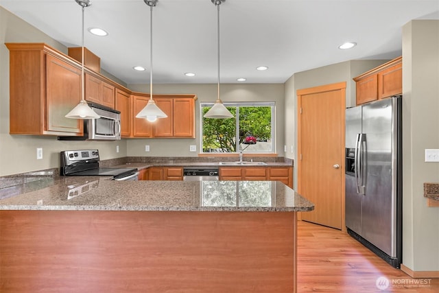 1321 Wilson Ave, Blaine, WA 98230 - kitchen featuring appliances with stainless steel finishes, a peninsula, light stone countertops, light wood-style flooring, and a sink