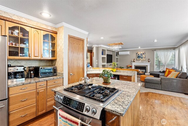 kitchen featuring open floor plan, a toaster, appliances with stainless steel finishes, and crown molding