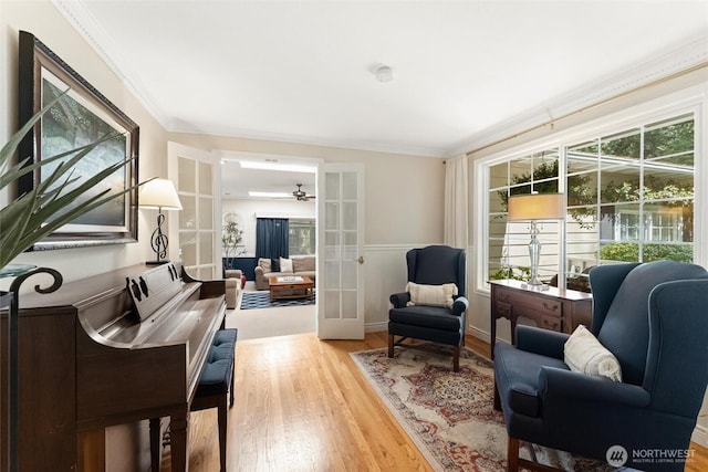 living area with french doors, wood finished floors, a ceiling fan, and ornamental molding