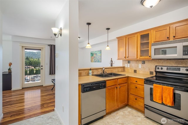 kitchen featuring stainless steel appliances, decorative backsplash, a sink, and brown cabinets