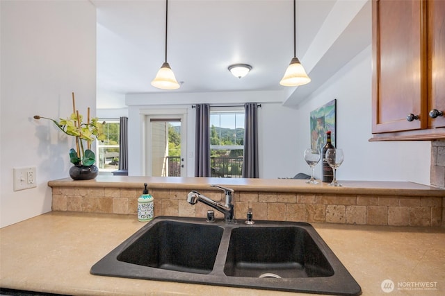 kitchen featuring a sink, a peninsula, decorative light fixtures, and light countertops