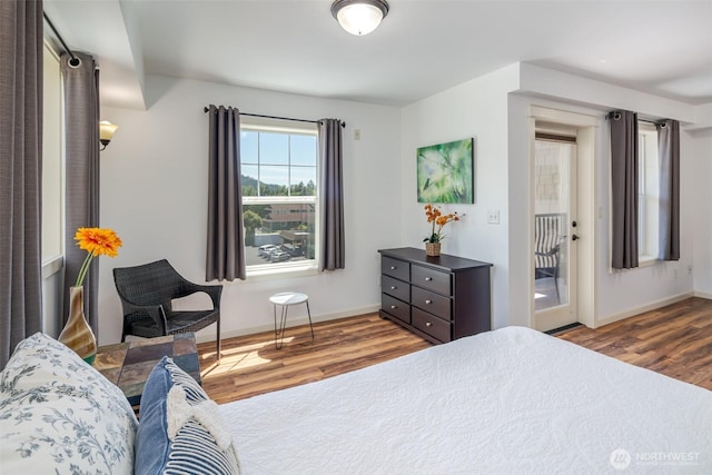 bedroom with wood finished floors, access to outside, and baseboards