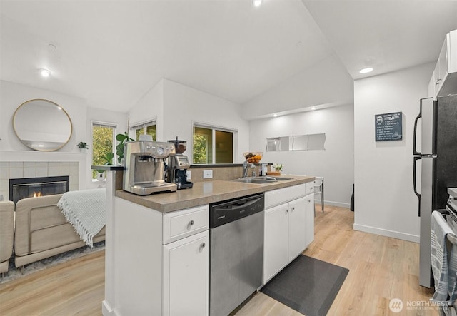 kitchen featuring a sink, light wood-style floors, white cabinets, and stainless steel dishwasher