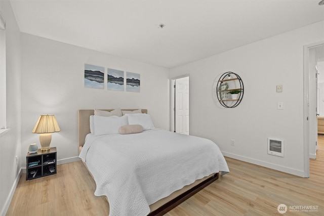 bedroom featuring baseboards, heating unit, and light wood-type flooring