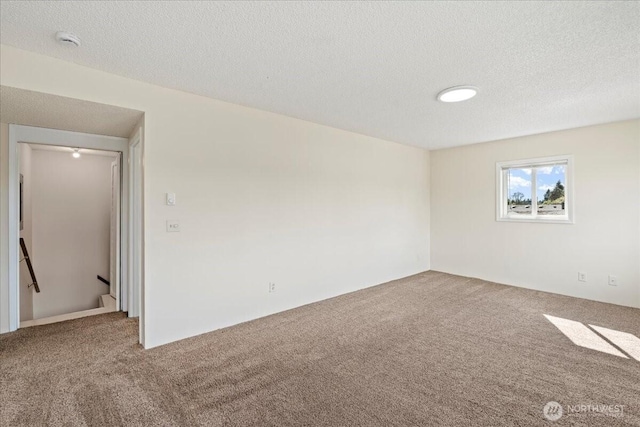 unfurnished room with carpet flooring and a textured ceiling