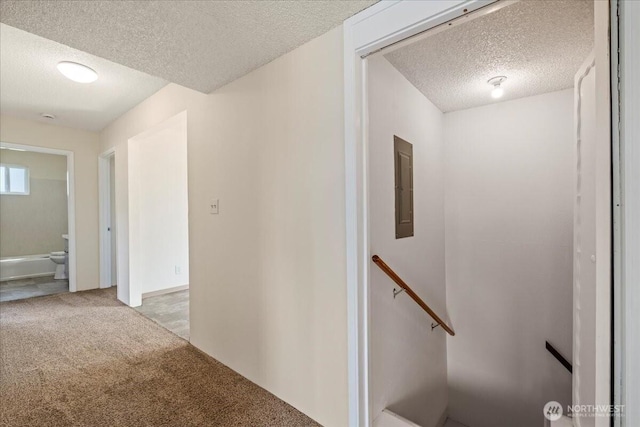 corridor featuring a textured ceiling, an upstairs landing, and light colored carpet