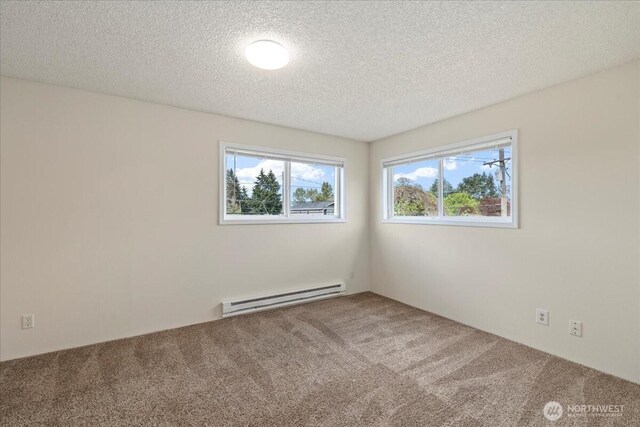 carpeted empty room featuring baseboard heating and a textured ceiling