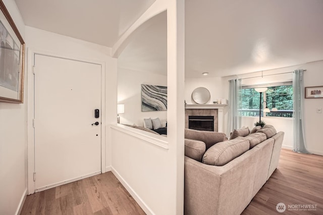 living room with light wood-style floors, baseboards, and a fireplace