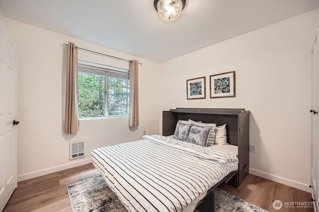 bedroom featuring visible vents, baseboards, and wood finished floors