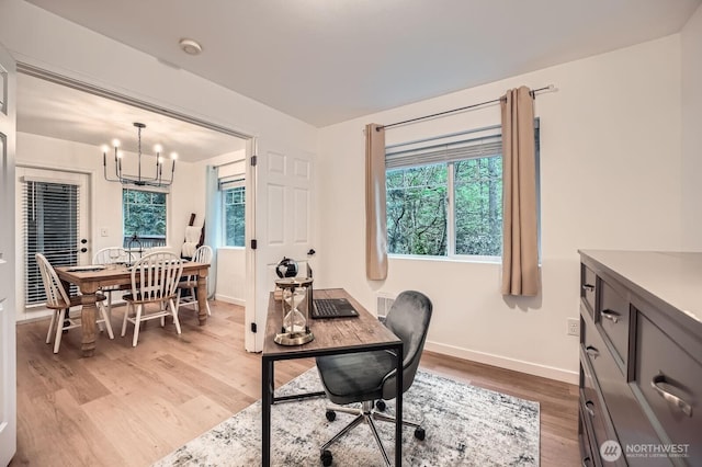 office space with an inviting chandelier, baseboards, and light wood-style flooring