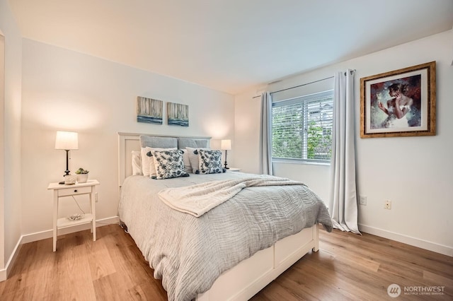 bedroom featuring baseboards and light wood finished floors