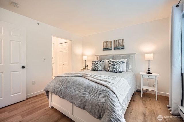 bedroom featuring light wood-type flooring, baseboards, and a baseboard heating unit