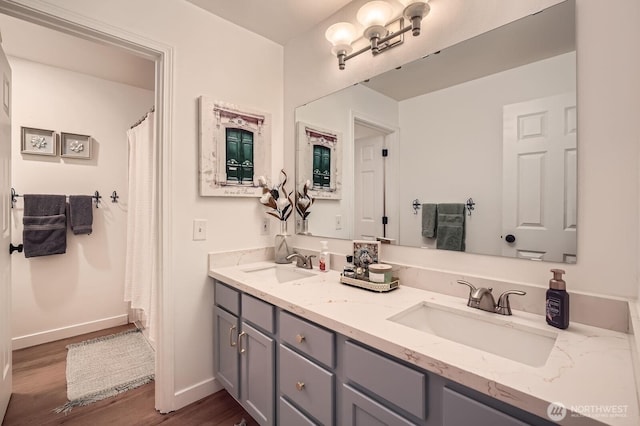 full bathroom with double vanity, a sink, and wood finished floors