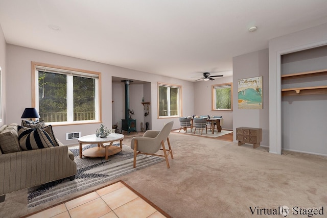 living room featuring ceiling fan, a wood stove, and visible vents